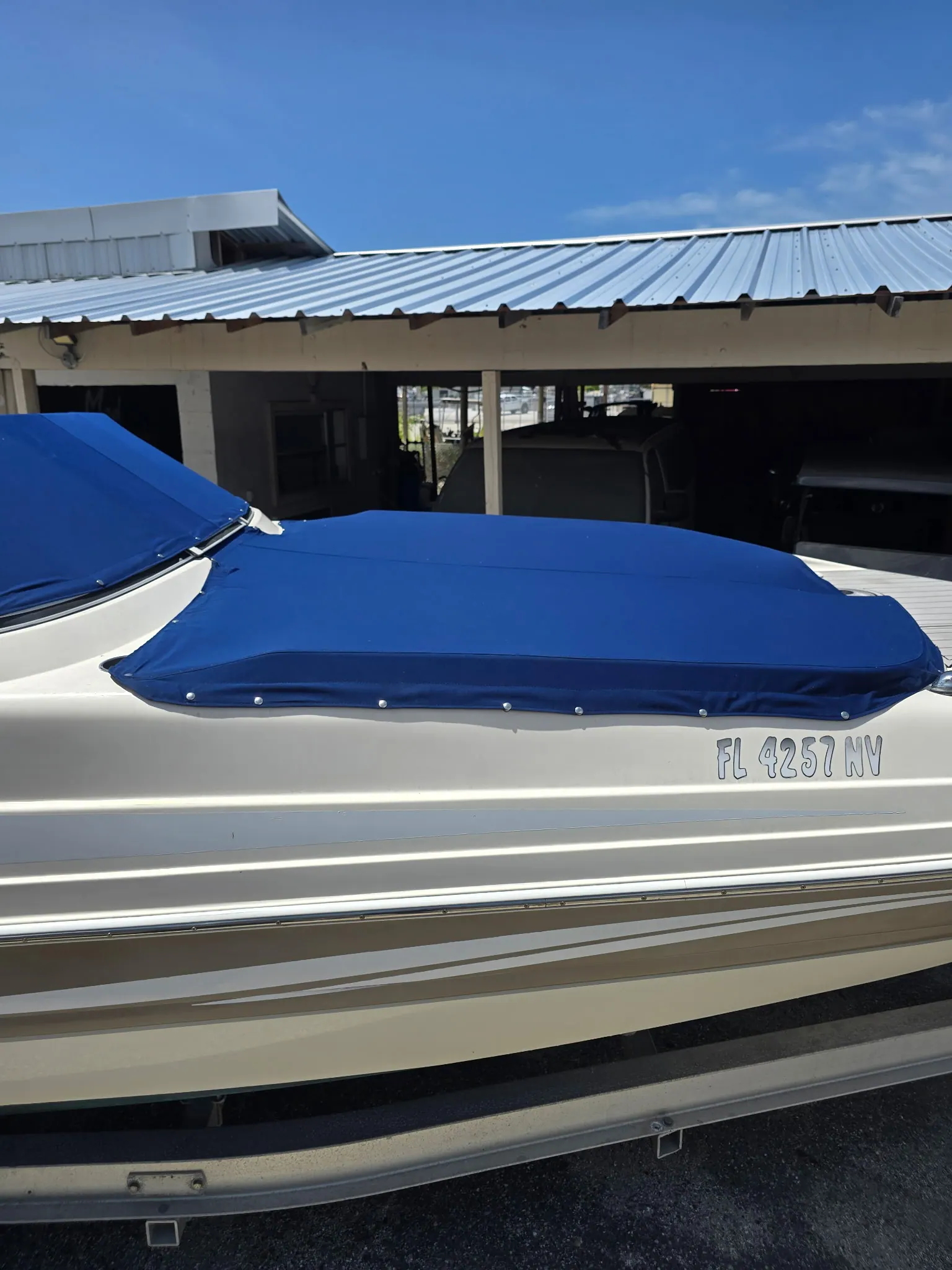 Royal blue custom boat cover on a trailered deck boat under a carport in Venice, FL