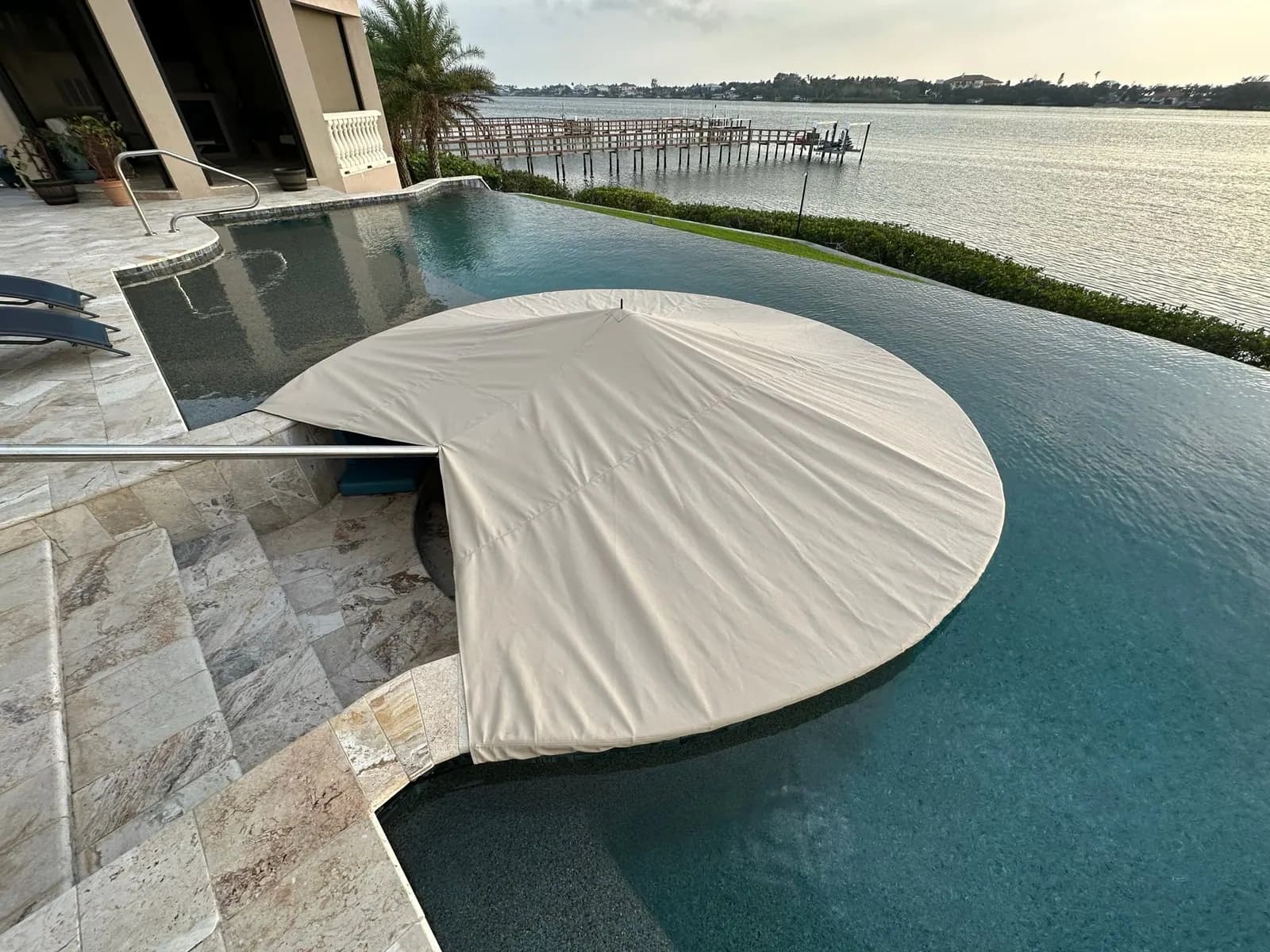 Custom tan cover installed over the curved poolside fire pit seating