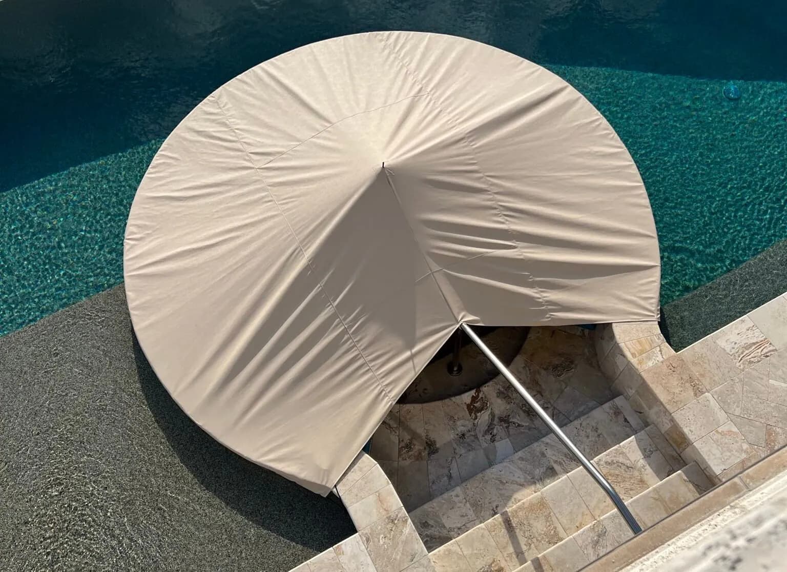 Round custom cover protecting the poolside fire pit seating
