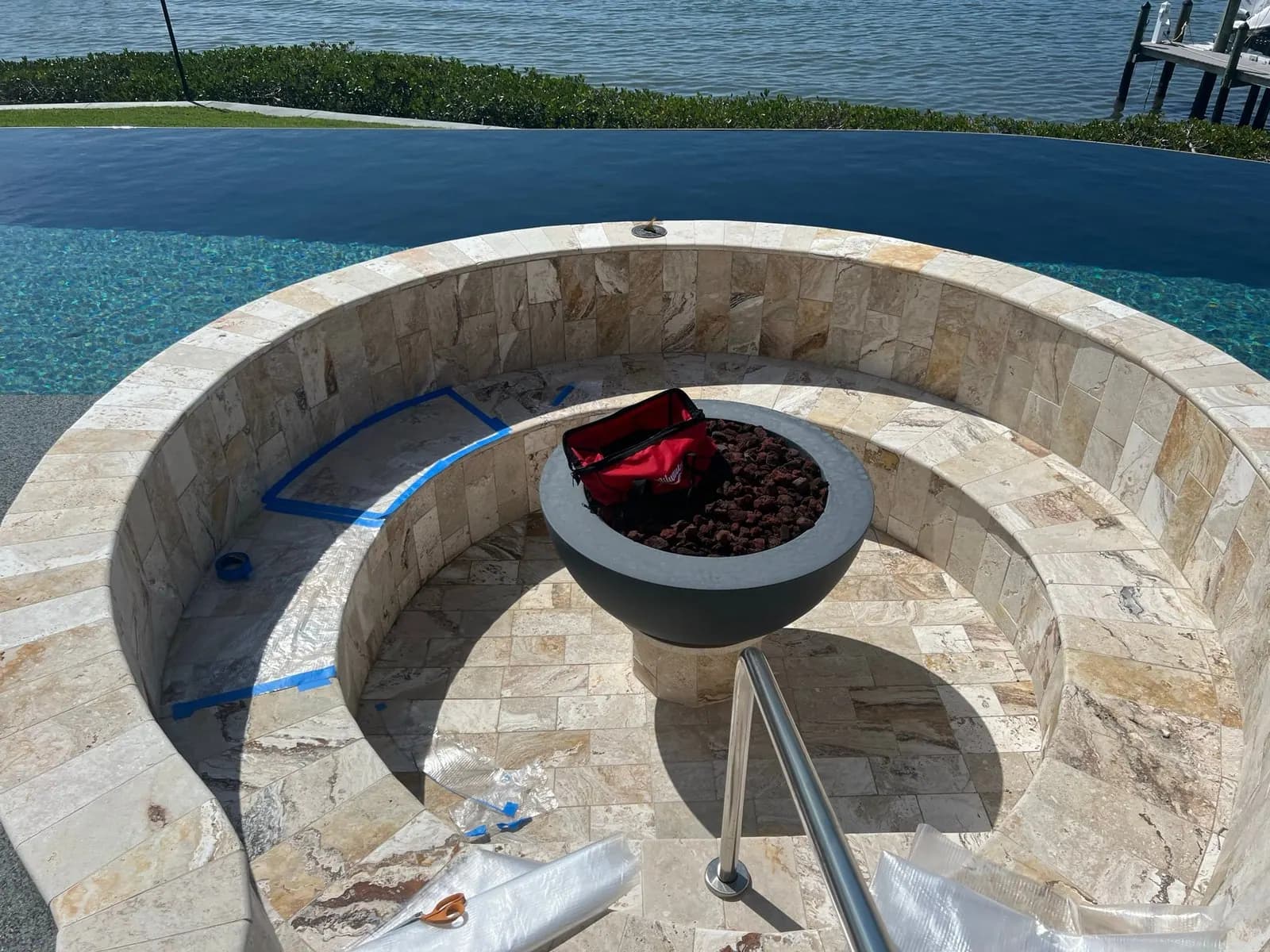 Curved stone fire pit seating being measured for custom cushions