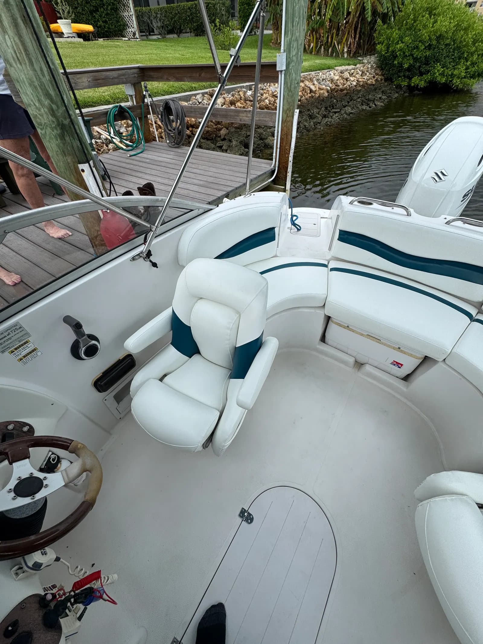 Deck boat cockpit seating in white marine vinyl with teal accents, at the dock