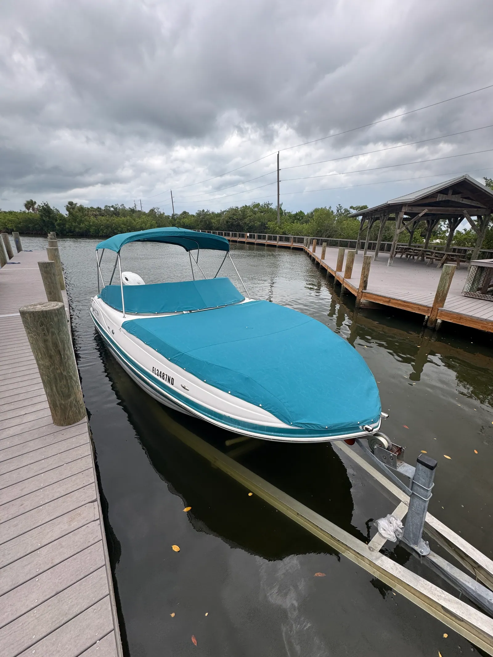 Dark teal mooring cover and matching bimini top on a Vectra deck boat at a canal dock in Venice, FL